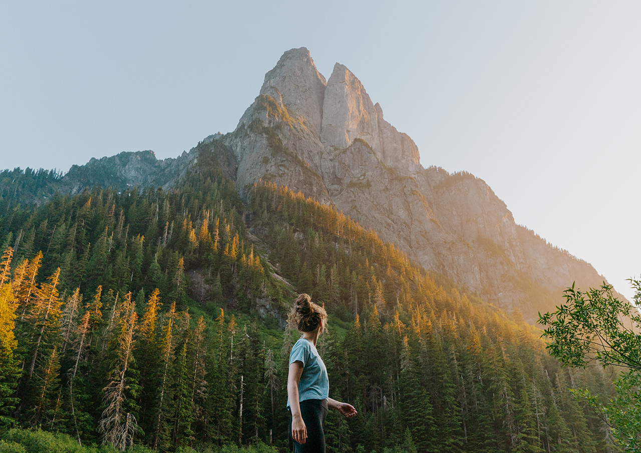 Woman standing in front of a mountain at sunset