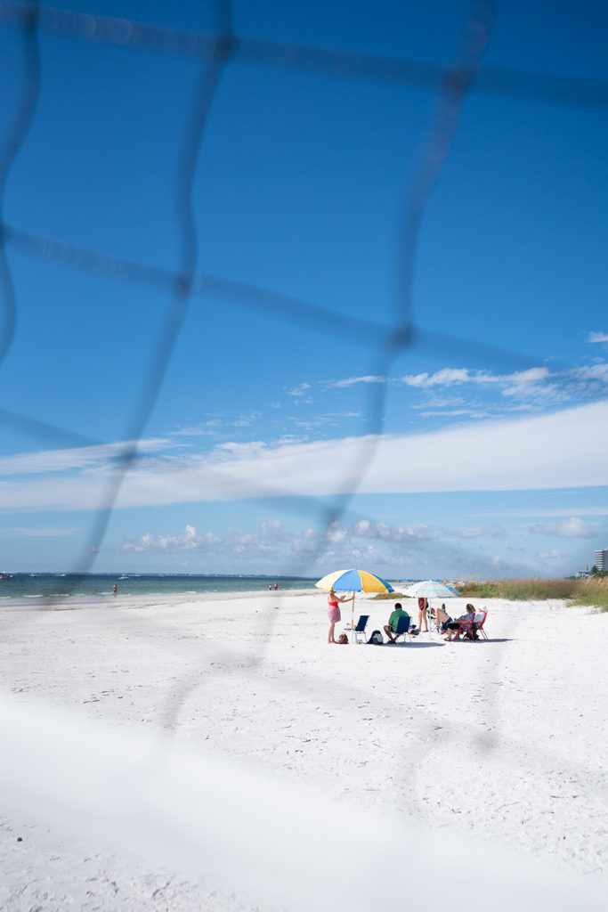 A family is enjoying the white sand beach and clear blue skies on Fort Myers Beach.